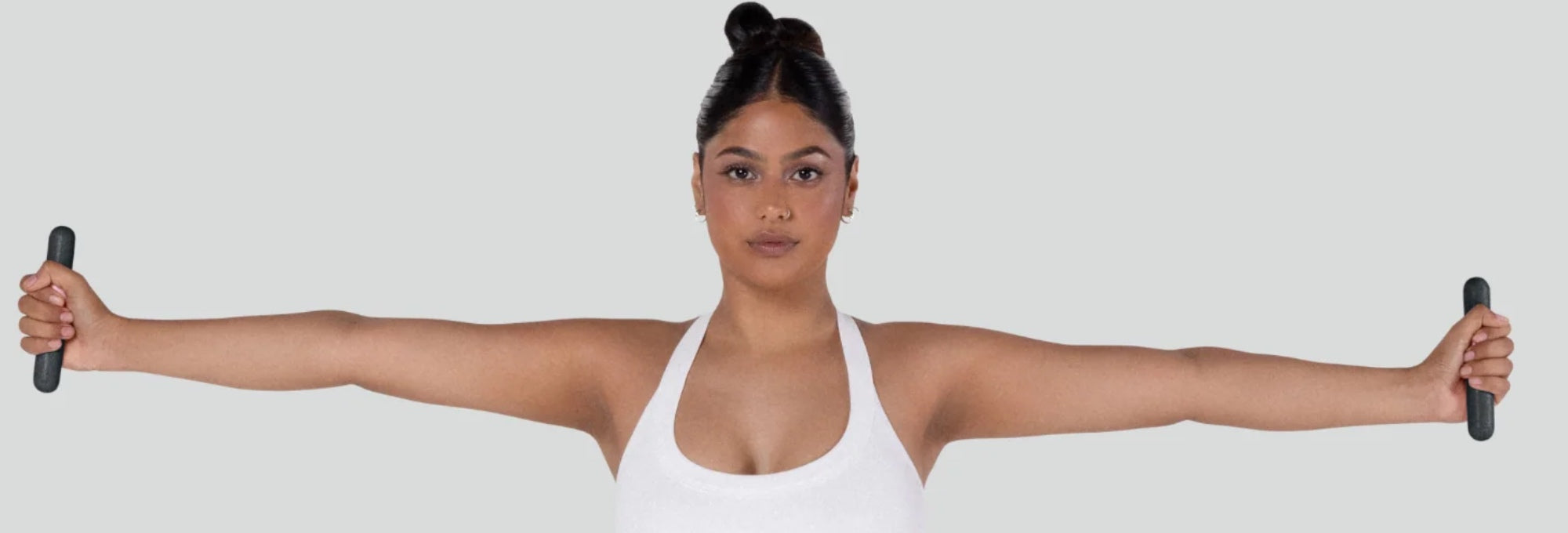 Model trainiert mit schwarzen bala Bars Handgewichten und ausgestreckten Armen für Schulter-, Arm- und Core-Training.